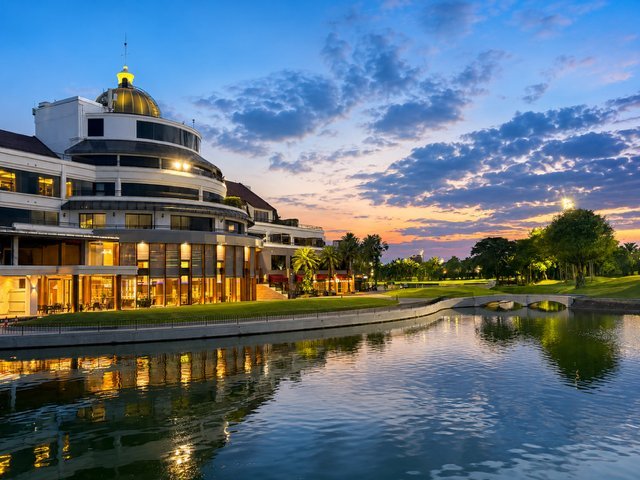 The Summit Windmill clubhouse lit at dusk, reflected in the lake