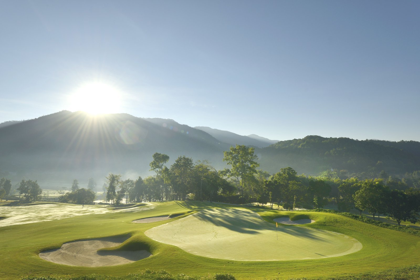 Sunrise over a bunkered green at Chiangmai Highlands, mountains in the distance