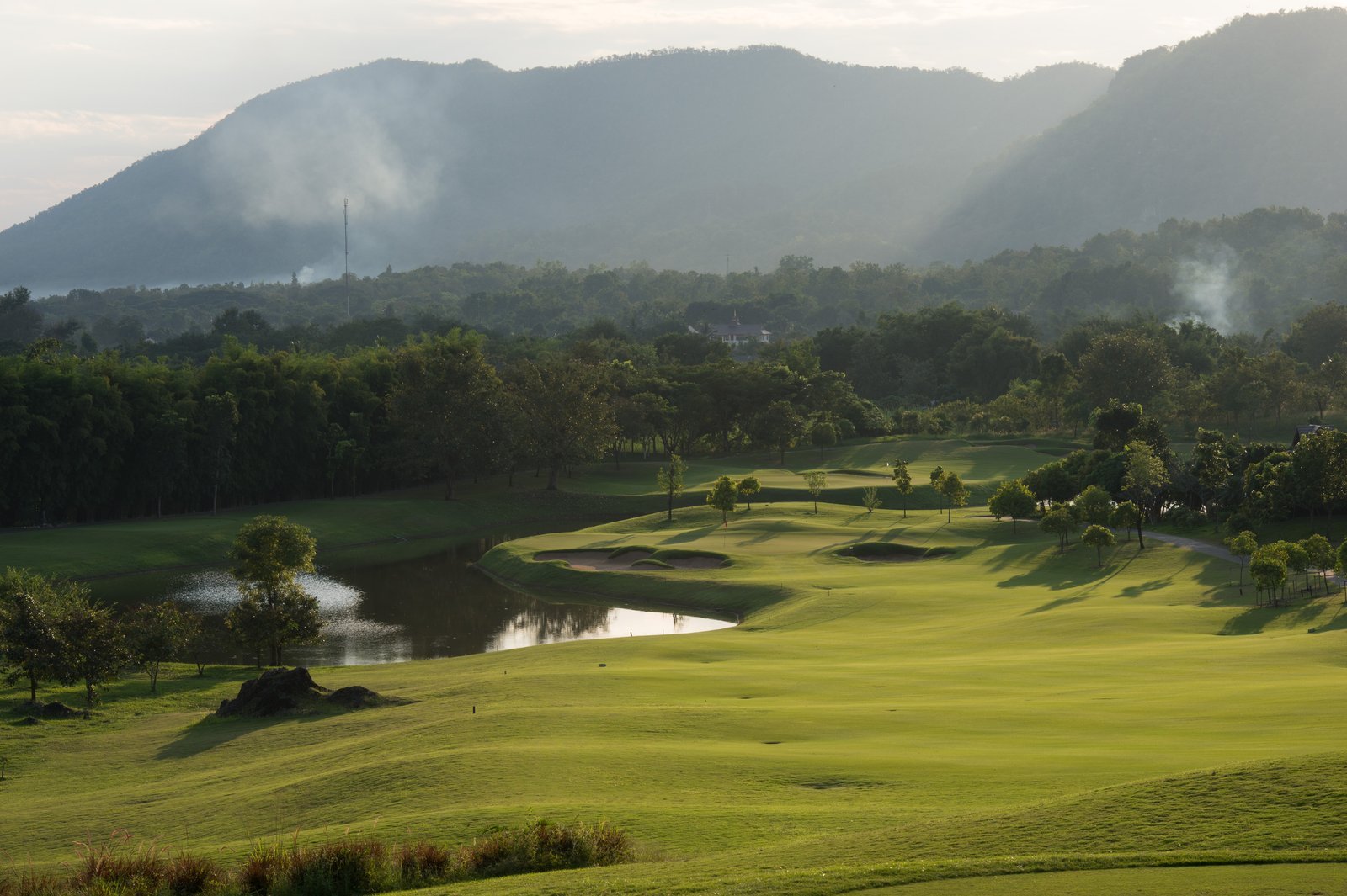 Rolling fairway and lake at Chiangmai Highlands with the hills beyond